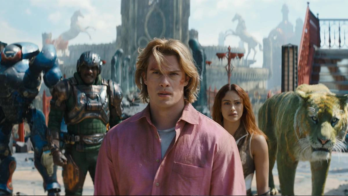 Mestres do Universo | Filme Entrega Exatamente o que Precisava e Abre Caminho Para um Universo Muito Maior 5 Esta é uma cena do filme live-action Mestres do Universo, com estreia prevista para junho de 2026. Adam está ao centro, camisa rosa, e o elenco de Eternia ao fundo.