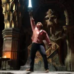 Esta é uma cena do filme live-action Mestres do Universo, estrelado por Nicholas Galitzine. A imagem mostra o protagonista em uma pose clássica, erguendo a Espada do Poder.