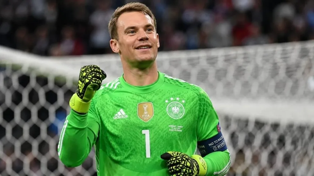 Neuer, uniforme da seleção alemã, punho direito fechado erguido, mão esquerda colada ao corpo, expressão de comemoração. Imagem gerada por IA.