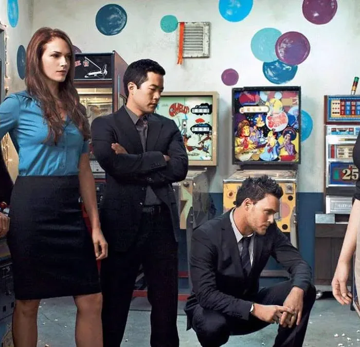 Esta imagem promocional mostra o elenco principal da série de televisão O Mentalista, atuando como seus personagens.