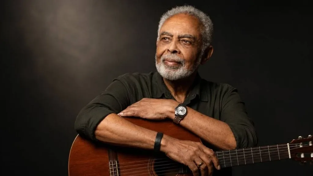 Gilberto Gil olhando para o lado, posando com braços sobre violão e sorrindo. Imagem gerada por IA.