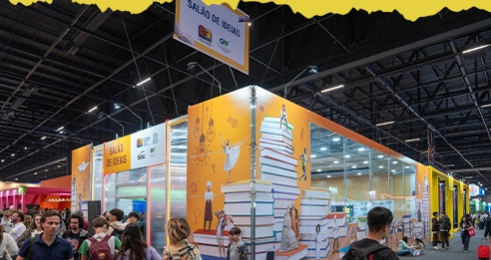 Bienal do Livro SP 2026 | Guia Completo de Ingressos e Programação 2 Salão de Ideias da Bienal do Livro, com estandes e espaços temáticos decorados com ilustrações de livros e pessoas, cercados por visitantes.