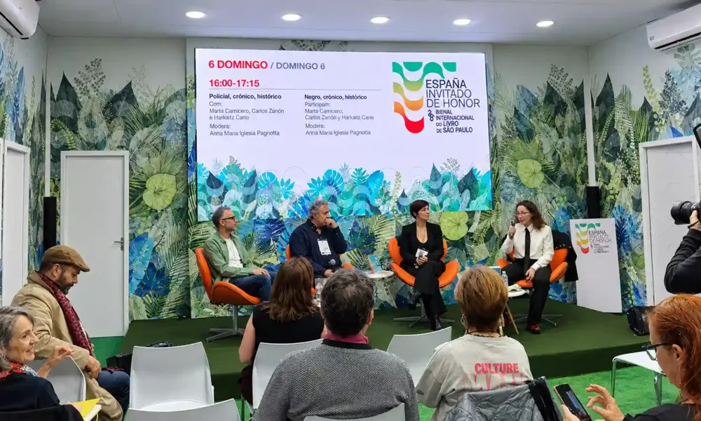 Convidados participam de um painel literário durante a Bienal do Livro SP 2026, no espaço da Espanha, país convidado de honra do evento. Os palestrantes conversam diante do público, com o telão exibindo a programação cultural.