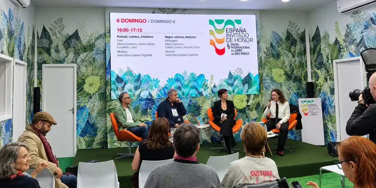 Convidados participam de um painel literário durante a Bienal do Livro SP 2026, no espaço da Espanha, país convidado de honra do evento. Os palestrantes conversam diante do público, com o telão exibindo a programação cultural.