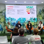 Convidados participam de um painel literário durante a Bienal do Livro SP 2026, no espaço da Espanha, país convidado de honra do evento. Os palestrantes conversam diante do público, com o telão exibindo a programação cultural.