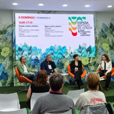 Convidados participam de um painel literário durante a Bienal do Livro SP 2026, no espaço da Espanha, país convidado de honra do evento. Os palestrantes conversam diante do público, com o telão exibindo a programação cultural.